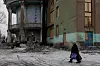 Une femme marchant près de la maison de la culture endommagée dans la ville de Bilytske, dans la région de Donetsk, le 3 mars.