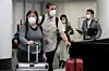 Des touristes en transition à l'aéroport de Chicago. Partout dans le monde, les gens tentent de se protéger contre le virus (Photo : AFP).