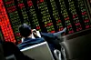 Un investisseur lit un journal devant un écran de cotation à Pékin le 20 janvier 2016.