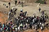 Des migrants passant, le 1er août, par une brèche dans la clôture séparant l'enclave espagnole de Ceuta de la ville marocaine de Fnideq.