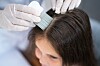 Un professionnel examine les cheveux d’un enfant avec un peigne fin pour contrôler son cuir chevelu.