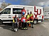 Des jeunes cyclistes médaillés posent avec leurs vélos devant des fourgons de la fédération luxembourgeoise.